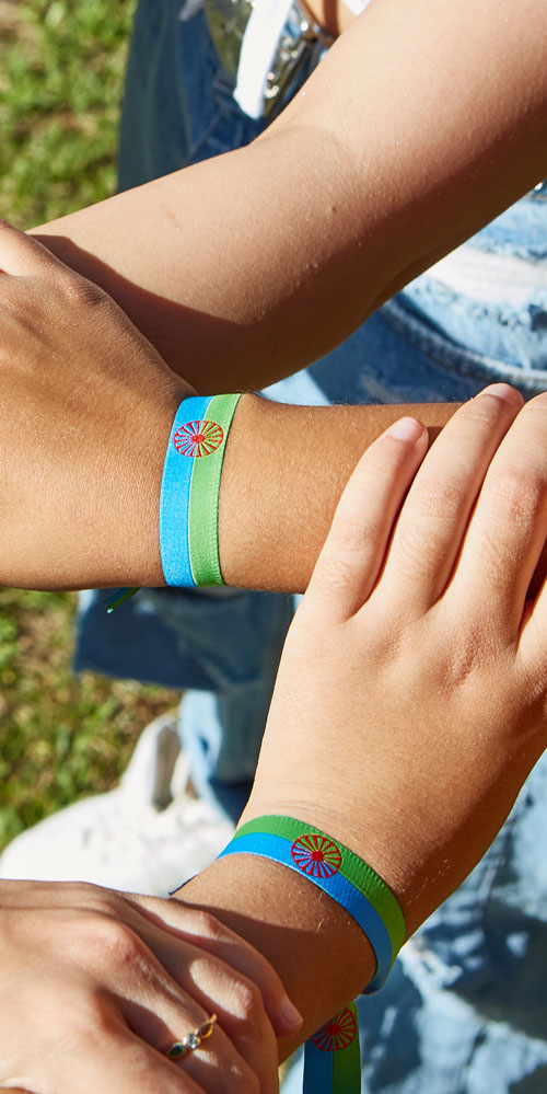 Imagen de manos con la pulsera de la bandera gitana